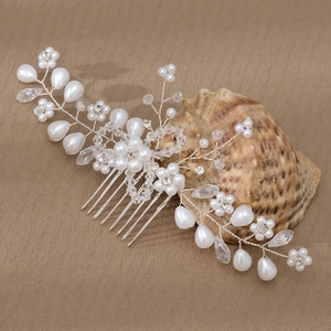 Elegante peineta de novia plateada con perlas y cristales sobre una concha decorativa
