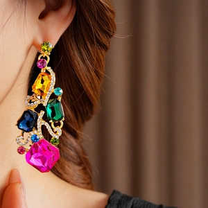 Close-up of vintage gold square earrings with colorful gemstones worn on a model's ear