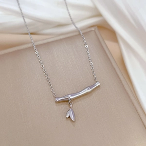 Minimalist silver bamboo joint necklace with a leaf pendant on silk fabric