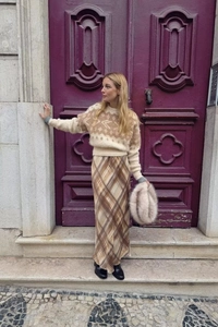 Outdoor street style view of beige knit sweater paired with a brown plaid long skirt