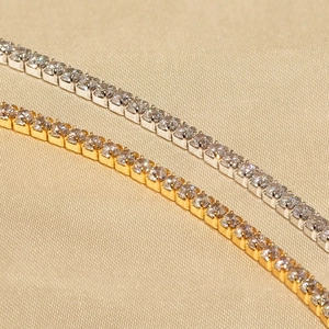 Close-up of gold and silver tennis bracelets with round-cut zircon stones in four-prong setting