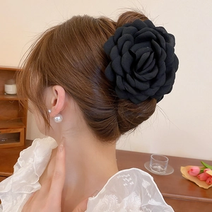 Detailed view of a black multi-layer fabric flower hair claw clip worn on a bun