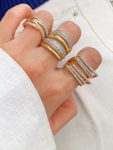 Dettaglio ravvicinato di anelli placcati oro 18k con zirconi impilati su un dito