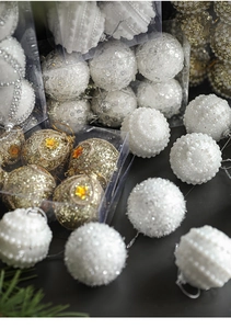 Detail of white pearl texture and gold glitter Christmas baubles in premium packaging