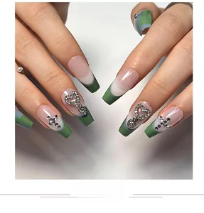 Close-up of green and pink French gradient press-on nails with heart charms and cross gems