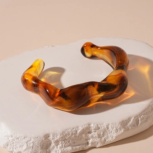 Macro detail of irregular amber acrylic resin bracelet on white stone base