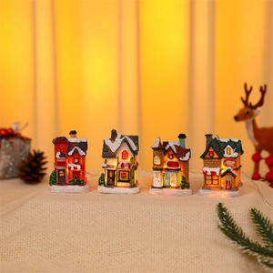 Close-up of four glowing miniature Christmas houses made of resin on a rustic burlap base