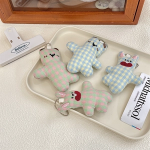 Close-up of checkered plush bear and bunny charms with metal bead chains in a tray