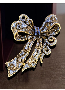 Detailed macro view of vintage bow brooch with faceted blue rhinestones on gold alloy