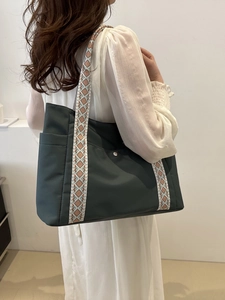 Borsa tote in nylon verde scuro con tracolla etnica geometrica indossata da una modella