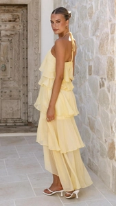 Detail of off-shoulder yellow chiffon dress with tiered ruffles and elegant halter neck