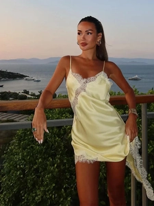 Pale yellow satin slip dress with white lace trim and V-neckline in a sunset beach setting