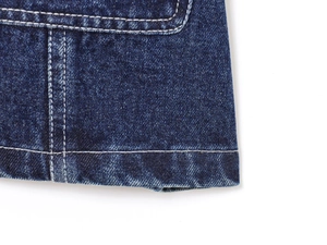 Gros plan sur la texture du denim bleu foncé et les surpiqûres blanches contrastées