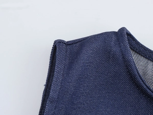 Vue détaillée de la texture du denim bleu foncé et des coutures sur l'encolure de la robe