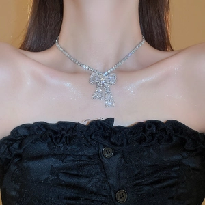 Close-up of a silver bow necklace featuring sparkling crystals on a female model