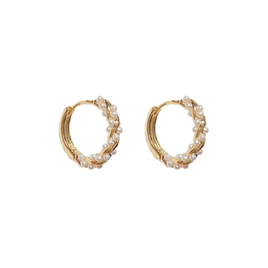 Close-up of C-shaped twisted gold earrings with woven freshwater pearls and gold beads