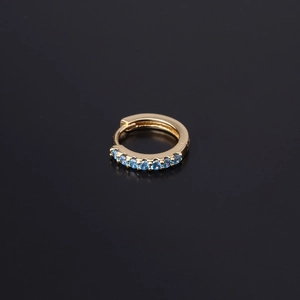 Close-up of golden hoop earring with polished finish and inlaid blue zircon crystals