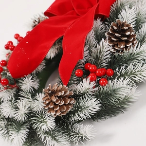 Christmas wreath with red velvet bow, pine cones, and red berries on snowy pine needles
