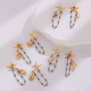 Macro shot of gold ocean-themed earrings featuring starfish, shell, and turtle bead charms