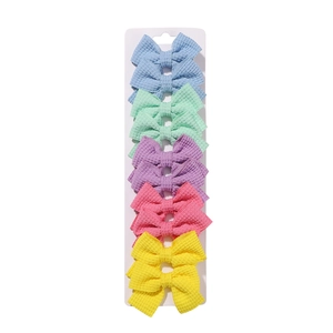 Macro detail of five macaron colored fabric bow hair clips on retail display card