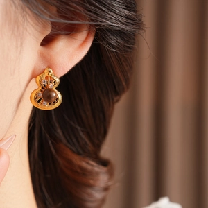 Macro detail of hollow gold gourd earrings with tiger eye stone and sparkling diamonds