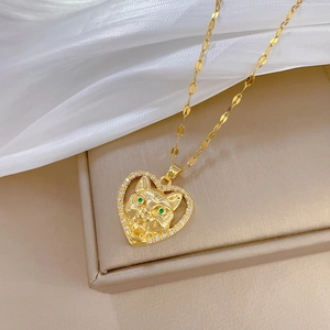 Close-up of golden heart pendant with a crystal-encrusted tiger head and green gem eyes