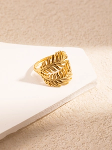 Detail of golden hollow palm leaf ring with intricate textures on a stone pedestal