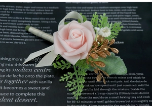 Detailed macro view of a light pink artificial rose boutonniere with golden accents and silk ribbon