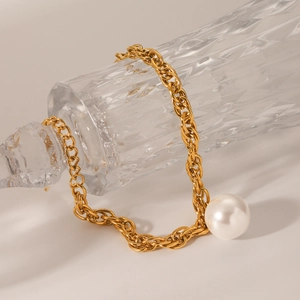 Detail of 18K gold stainless steel chain with large pearl on vintage glass bottle