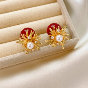 Macro detail of luxury fireworks earrings with gold petals and a white center pearl