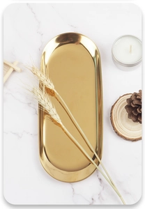 Close-up of golden oval stainless steel tray with mirror finish on marble surface