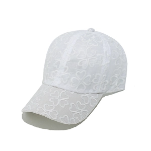 Dettaglio ravvicinato del cappellino bianco in pizzo con motivi floreali all'uncinetto