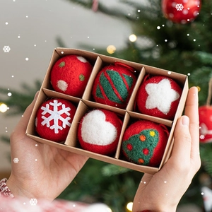Hand holding a set of 6 Christmas wool felt ornaments in a kraft gift box