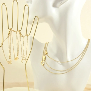 Close-up of gold 18K plated alphabet pendants A, B, and C shown in stacked style