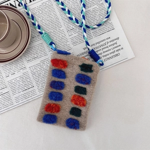 Artistic plush mini bag with colorful 3D patches and thick braided strap on newspaper