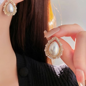 Detailed view of gold teardrop pearl earrings with zircon inlay on model