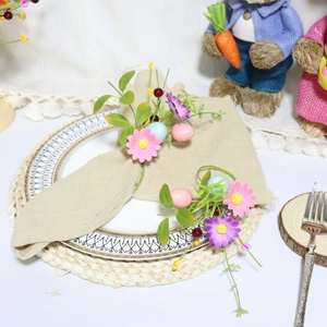 Easter egg napkin rings with pink floral accents and green leaves on ceramic plates