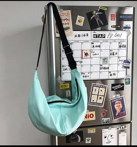 Detail of mint green nylon crescent bag hanging with adjustable strap and plastic buckle