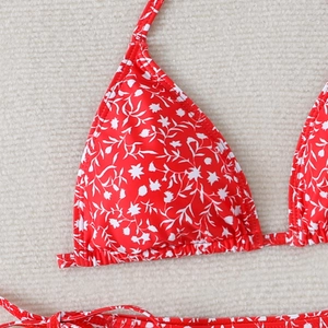 Detail of red halter bikini top with white floral print and ruffled triangle cup edges