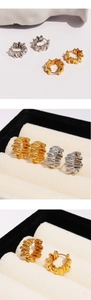 Macro detail of gold and silver textured ribbon wave earrings in a jewelry box