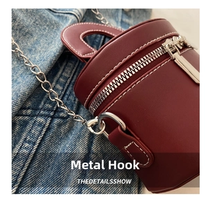 Détail du crochet en métal argenté et couture sur le sac cylindrique bordeaux