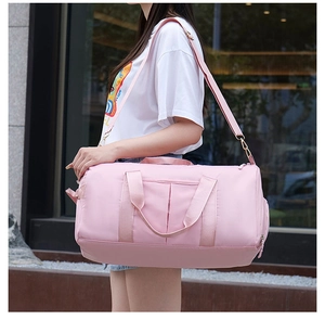 Pink fitness travel bag with shoulder strap shown being carried by a model outdoors