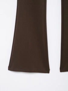 Detail shot of deep brown flared trousers showing high-quality stitching and fabric texture