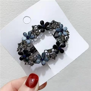 Vintage hollow metal flower hair clip with deep blue rhinestones on a display card