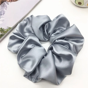 Detailansicht eines silbergrauen Satin-Scrunchie mit dichten Falten und feinem Glanz