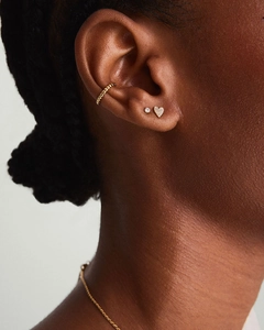 Detail shot of heart-shaped zircon earrings and gold textured ear cuff on model