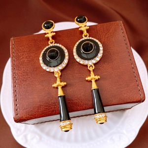Close-up of vintage black and gold enamel earrings with rhinestone details on leather