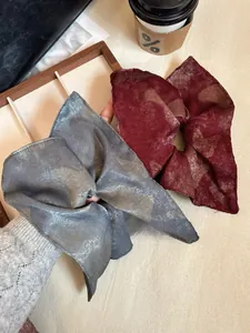 Close-up of vintage satin scrunchies in burgundy and dark grey with silky texture