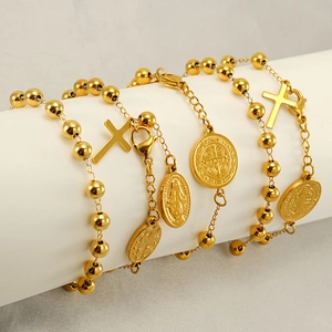 Detailed close-up of golden religious bracelets with cross and Mary charms on a stand
