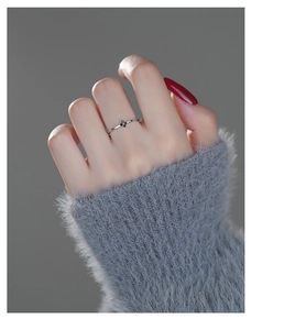 Close-up of a slim S999 silver clover ring with black stones worn on a finger